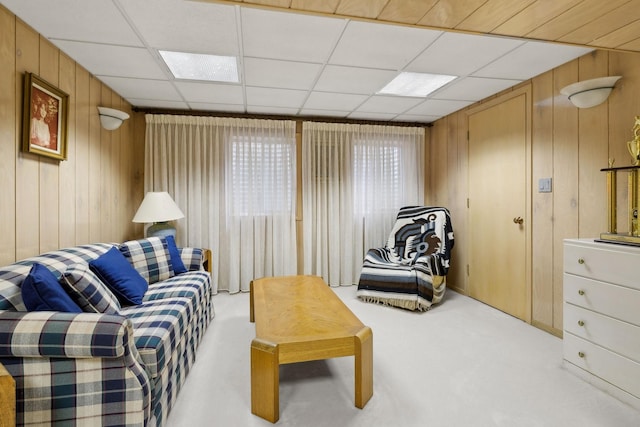 interior space featuring carpet flooring, a drop ceiling, and wood walls