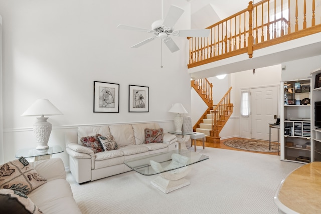 living room with ceiling fan, a towering ceiling, and light hardwood / wood-style flooring