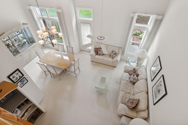 carpeted living room with a towering ceiling and a notable chandelier