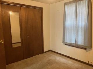 unfurnished bedroom featuring light colored carpet and a closet