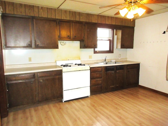 kitchen featuring gas range gas stove, light hardwood / wood-style floors, ceiling fan, dark brown cabinets, and sink