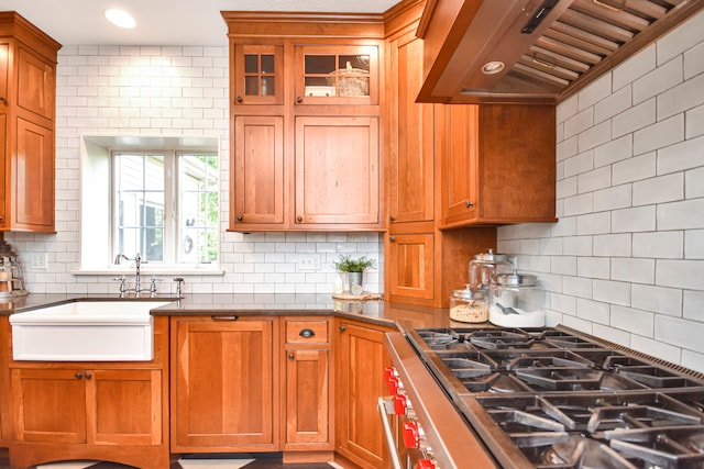 kitchen featuring stainless steel range oven, custom exhaust hood, backsplash, and sink