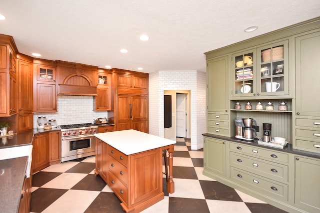 kitchen featuring green cabinets, tasteful backsplash, designer stove, a center island, and premium range hood