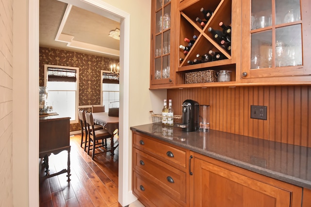 bar with dark wood-type flooring and dark stone counters