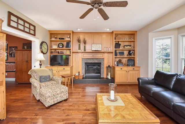 living room with hardwood / wood-style floors, ceiling fan, and a fireplace