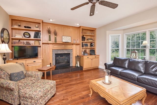 living room with dark wood-type flooring, ceiling fan, and a fireplace