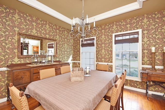 dining room with hardwood / wood-style floors, ornamental molding, a tray ceiling, and a notable chandelier