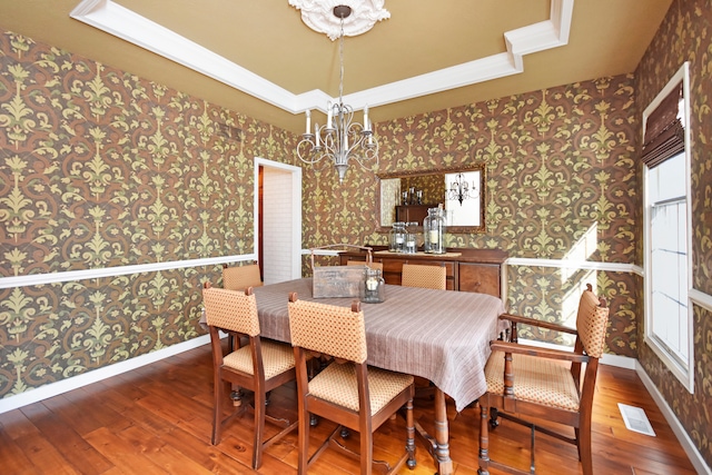 dining room featuring wood-type flooring, a tray ceiling, and an inviting chandelier