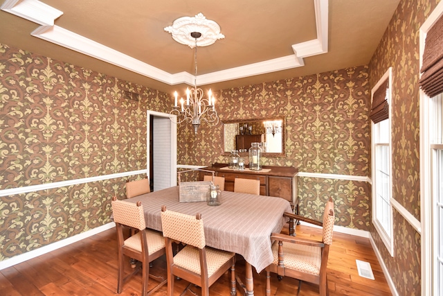 dining space with a chandelier, hardwood / wood-style flooring, and a raised ceiling