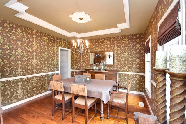 dining space featuring wood-type flooring, a chandelier, and a tray ceiling