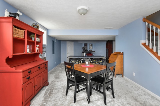 dining room featuring a textured ceiling and light carpet