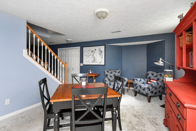 dining area with light colored carpet and a textured ceiling