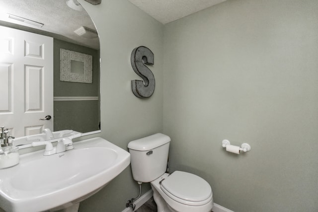 bathroom with toilet, sink, and a textured ceiling