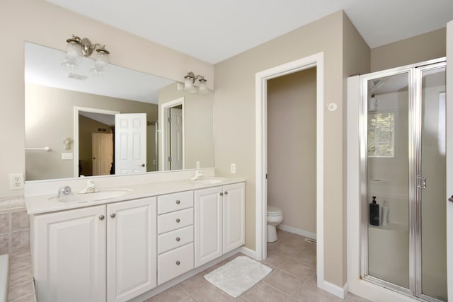 bathroom featuring toilet, vanity, tile patterned flooring, and a shower with shower door