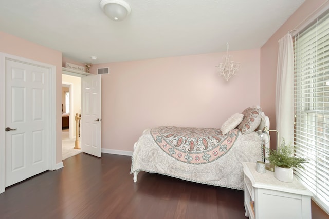 bedroom featuring dark hardwood / wood-style flooring, multiple windows, and a chandelier