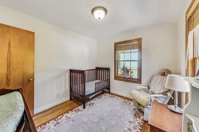 bedroom featuring a crib, lofted ceiling, and hardwood / wood-style floors