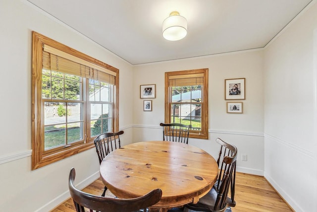 dining room featuring light wood-type flooring, a healthy amount of sunlight, and crown molding