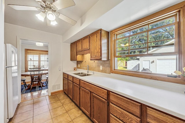 kitchen featuring ceiling fan, light tile patterned floors, sink, tasteful backsplash, and white fridge