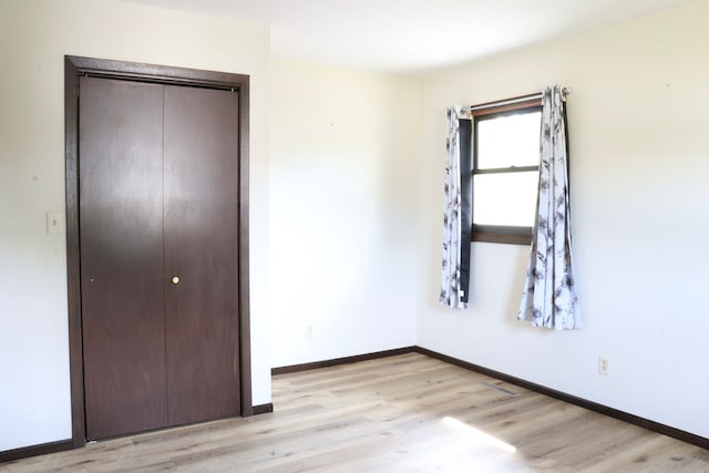 unfurnished bedroom featuring light hardwood / wood-style flooring and a closet