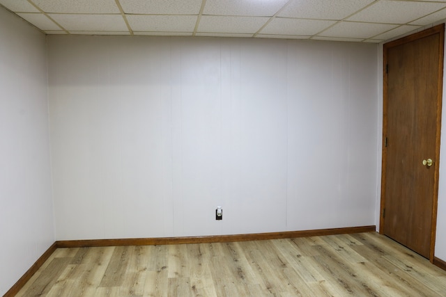 spare room featuring a paneled ceiling and light hardwood / wood-style flooring