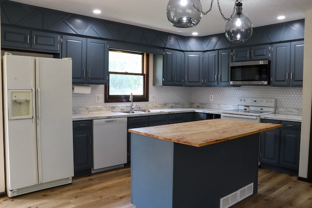 kitchen with sink, a kitchen island, white appliances, hardwood / wood-style floors, and butcher block countertops