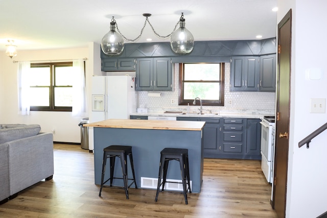 kitchen featuring pendant lighting, sink, a kitchen island, a breakfast bar area, and hardwood / wood-style floors