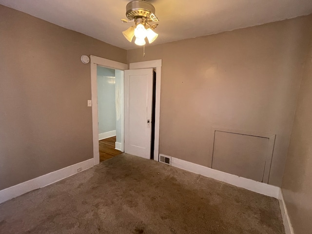 empty room with ceiling fan and dark colored carpet