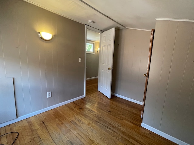 empty room with wood-type flooring, wood walls, and vaulted ceiling