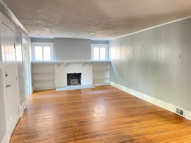 unfurnished living room with hardwood / wood-style flooring, a fireplace, and a healthy amount of sunlight