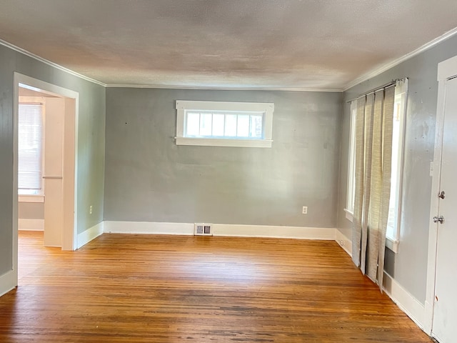 empty room featuring a textured ceiling, crown molding, and hardwood / wood-style floors