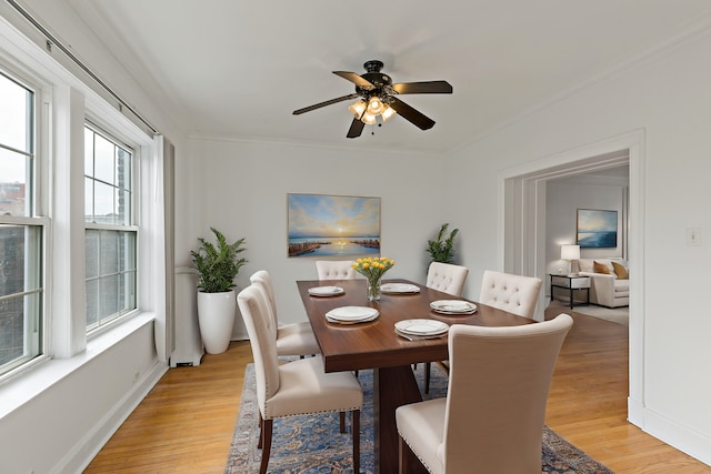 dining area featuring baseboards, crown molding, and light wood finished floors