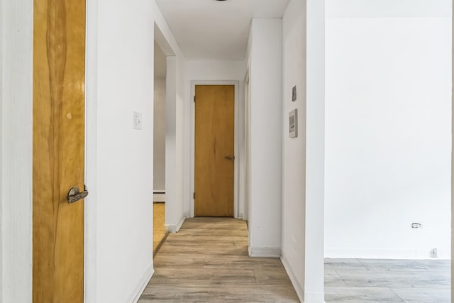 hallway featuring a baseboard heating unit and light wood-type flooring