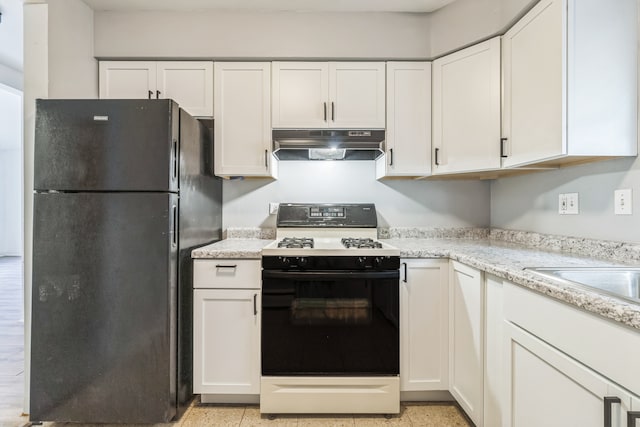 kitchen featuring light stone counters, black fridge, white range, and white cabinets