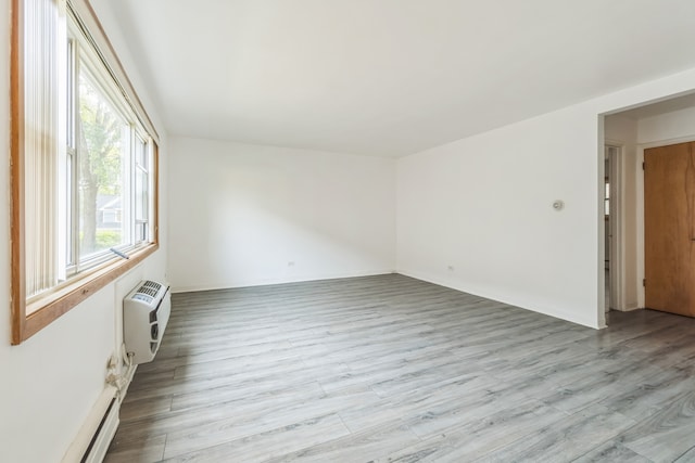 empty room with light wood-type flooring and a baseboard heating unit