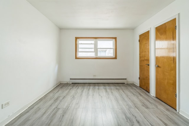 unfurnished bedroom with light hardwood / wood-style floors and a baseboard heating unit