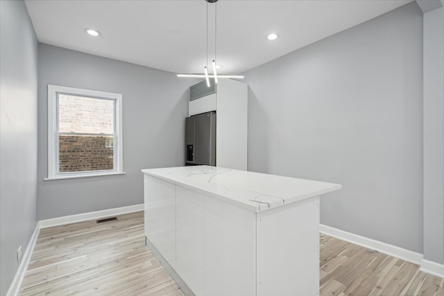 kitchen featuring hanging light fixtures, a kitchen island, stainless steel fridge with ice dispenser, white cabinetry, and light wood-type flooring