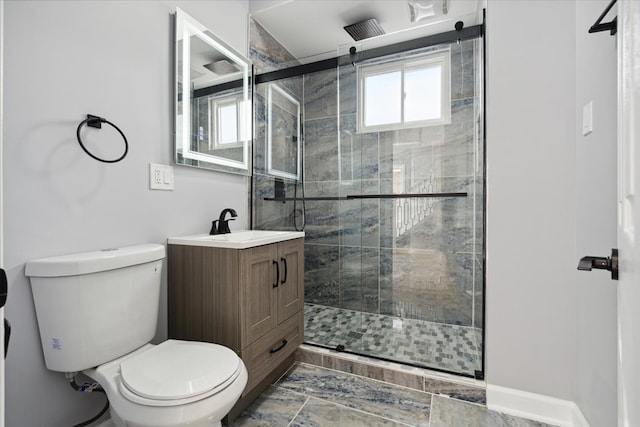 bathroom featuring vanity, a shower with shower door, and toilet