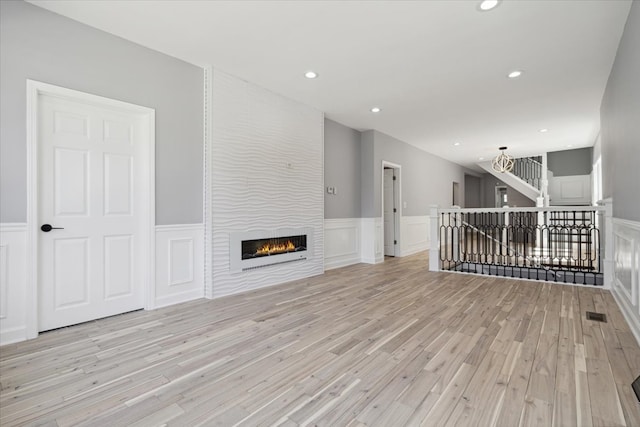 unfurnished living room with a large fireplace and light hardwood / wood-style flooring