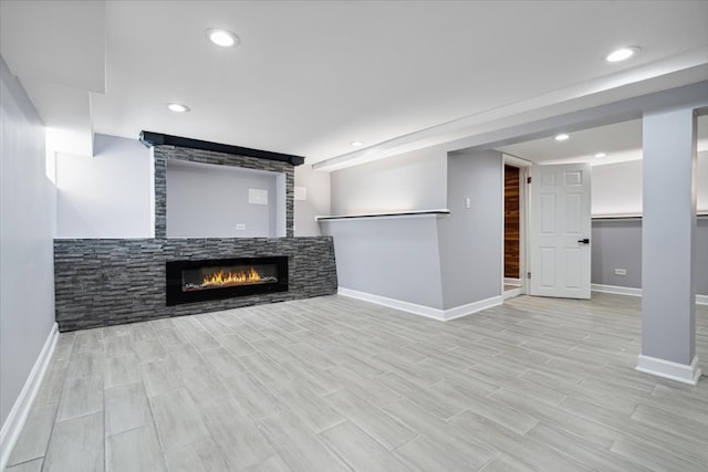 unfurnished living room with light wood-type flooring and a stone fireplace