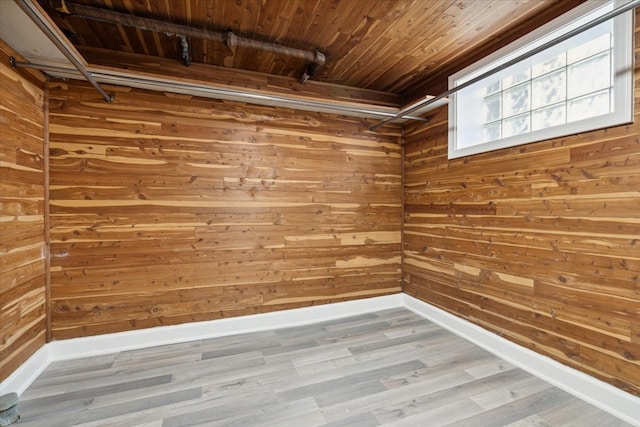 unfurnished room with wooden ceiling, wood-type flooring, and wooden walls