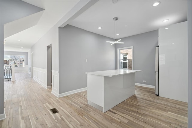 kitchen featuring decorative light fixtures, light hardwood / wood-style floors, and a kitchen island