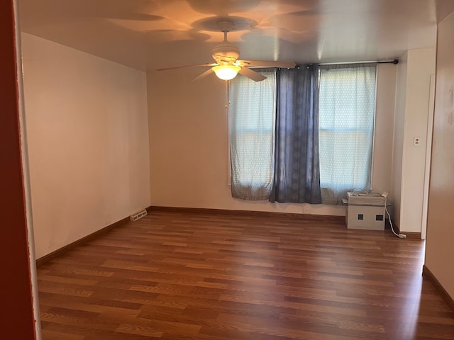 empty room with ceiling fan, a healthy amount of sunlight, and dark hardwood / wood-style floors