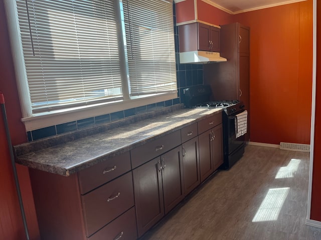 kitchen with black gas stove, backsplash, hardwood / wood-style floors, dark brown cabinetry, and crown molding