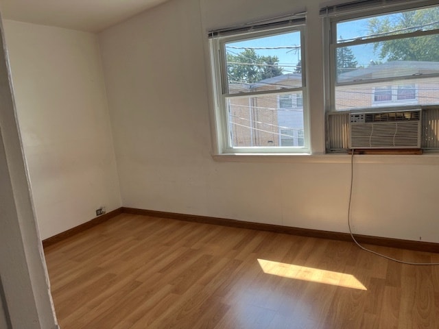 unfurnished room with cooling unit and light wood-type flooring