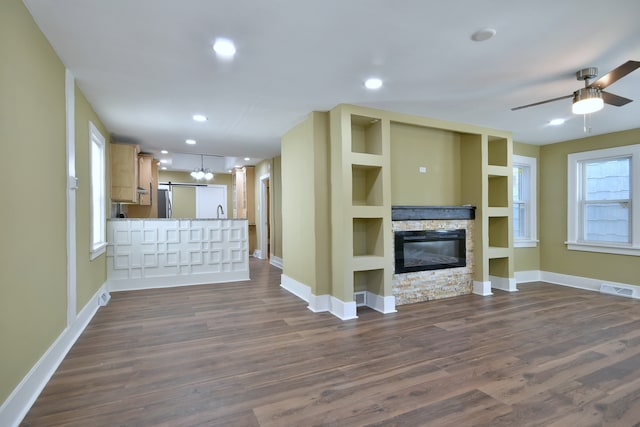 unfurnished living room featuring built in features, ceiling fan, a fireplace, and dark hardwood / wood-style flooring