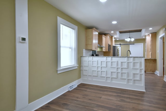 kitchen with light brown cabinetry, appliances with stainless steel finishes, dark wood-type flooring, kitchen peninsula, and decorative backsplash