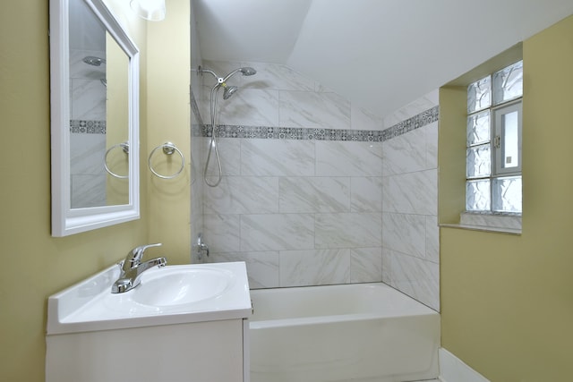 bathroom with vanity, vaulted ceiling, and tiled shower / bath combo