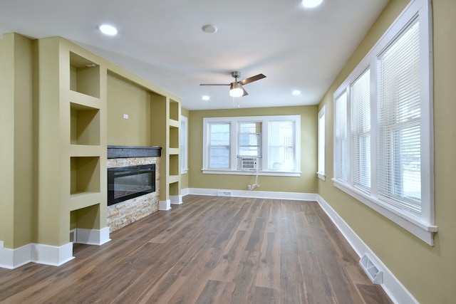 unfurnished living room with dark wood-type flooring, ceiling fan, a fireplace, and plenty of natural light