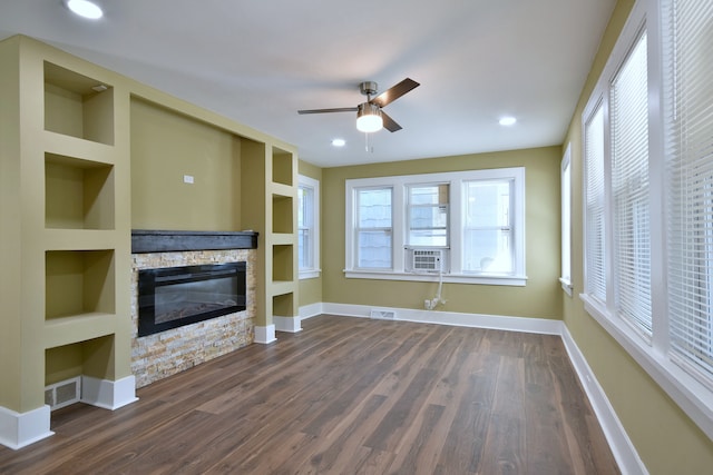 unfurnished living room featuring plenty of natural light, ceiling fan, dark wood-type flooring, and a fireplace