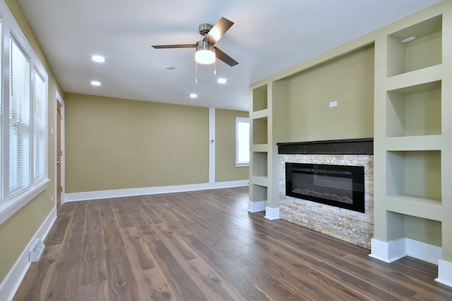 unfurnished living room with dark wood-type flooring, built in shelves, ceiling fan, and a fireplace